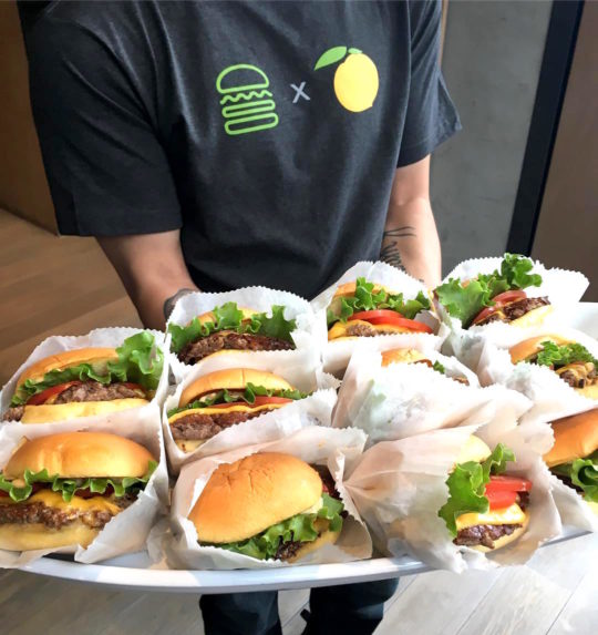 shake shack employee holding a platter of burgers