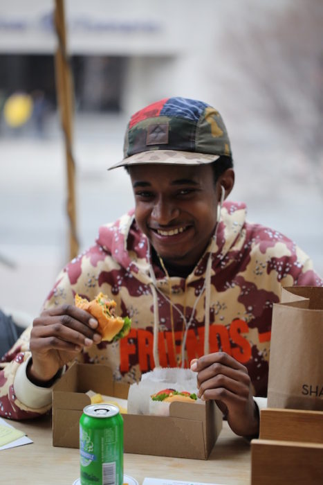 customer smiling and eating a shake shack burger