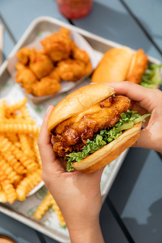 A Shake Shack Hot Honey Chicken sandwich held with two hands