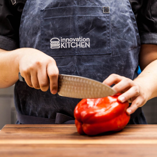 Knife cutting through a red bell pepper