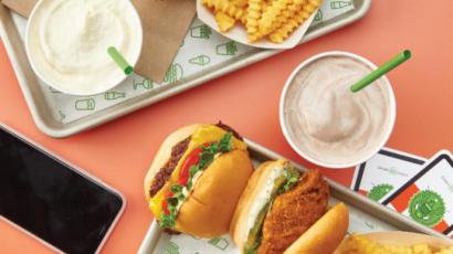 two food trays with fries, shakes and burgers on them, pictured from above