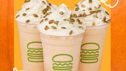 three shakes with seed toppings. The background is different shades of orange, and there are outlines of three pumpkins.